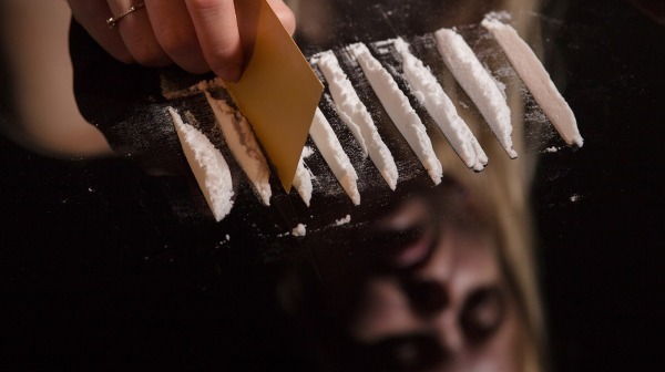 cocaine or other drugs cut with card on mirror with female reflection, hand dividing white powder narcotic